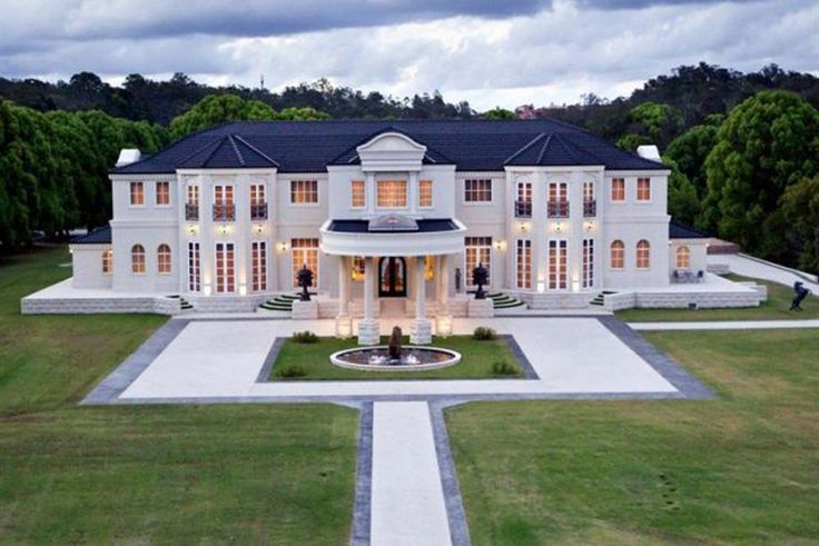 an aerial view of a large white house in the middle of a grassy area with trees