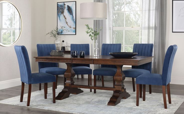 a dining room table with blue chairs in front of a white rug on the floor