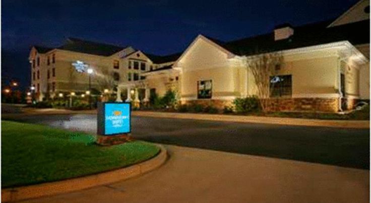 the front entrance to a hotel at night with street lights and grass on the side walk