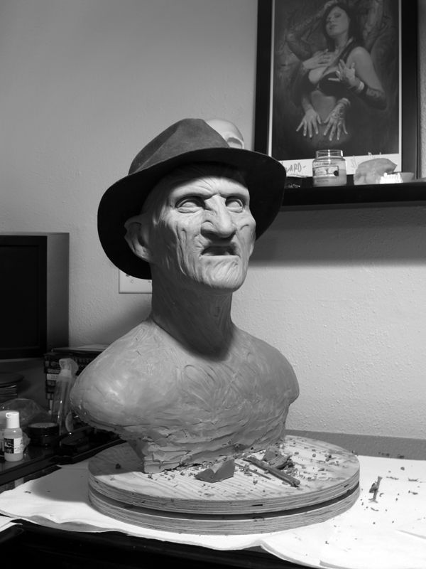 a statue of a man with a hat on top of a desk next to a painting