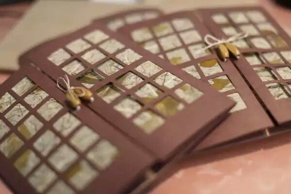 three pieces of brown and white paper with gold foiled squares on them sitting on a table