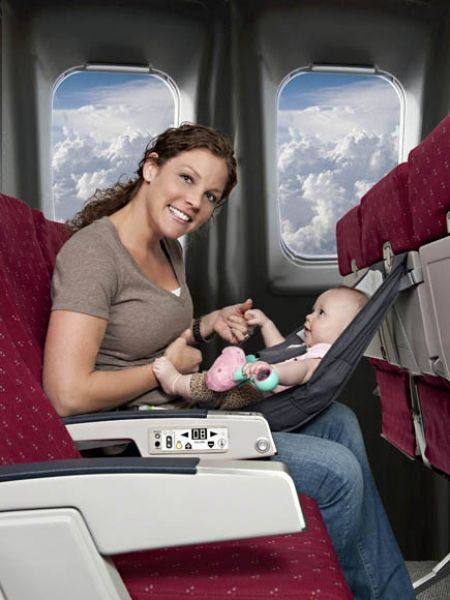 a woman sitting on an airplane with a baby in her lap and the seat is empty