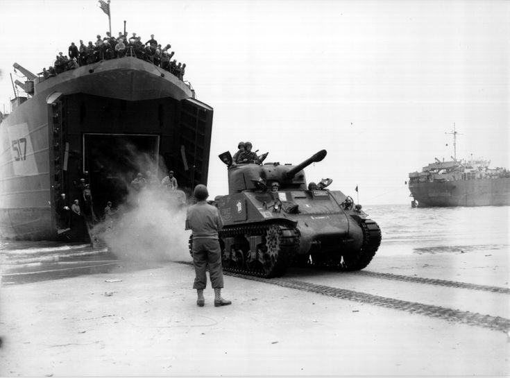 an old photo of men standing in front of tanks on the ground next to a ship