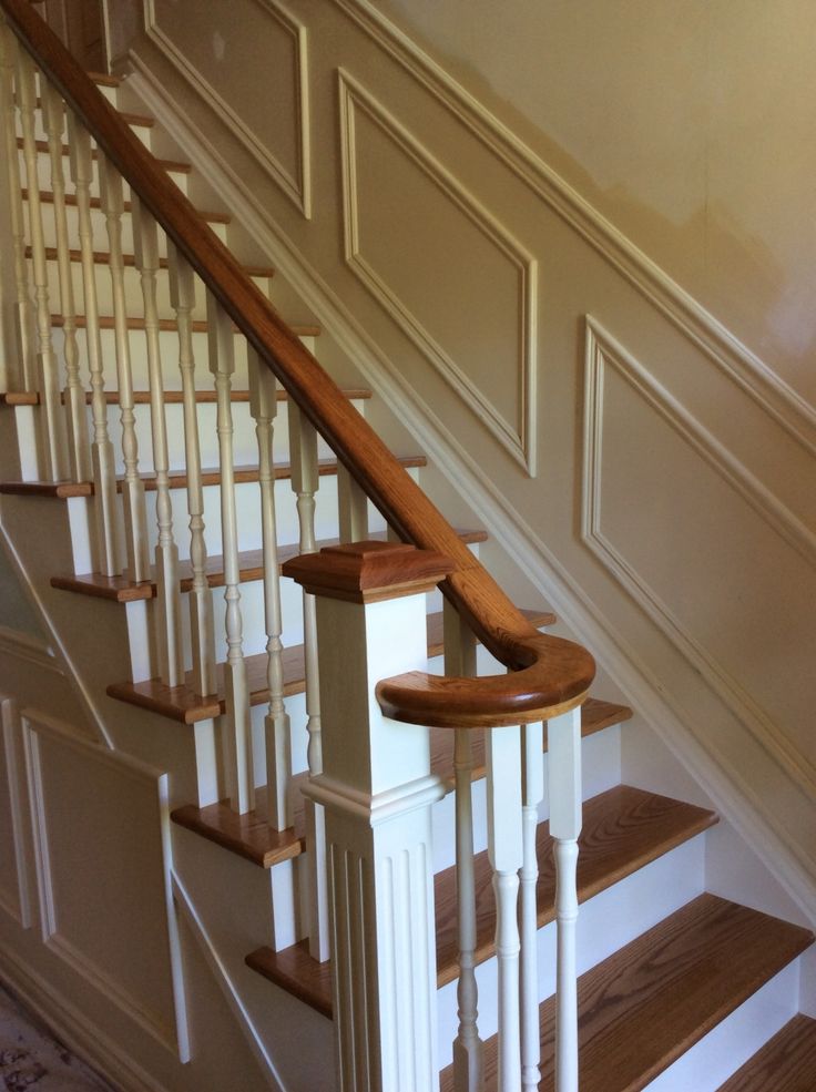 a wooden banister next to a set of stairs with white railing and wood handrails