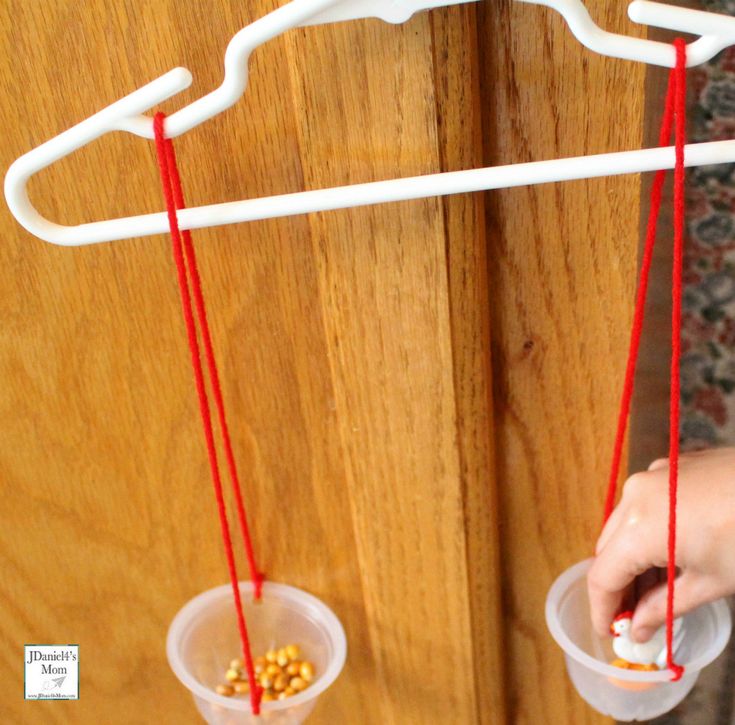 two plastic cups filled with candy sitting on top of a wooden door sill next to a white hanger