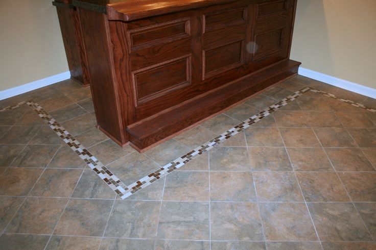 a wooden counter sitting in the middle of a room with tile flooring on it