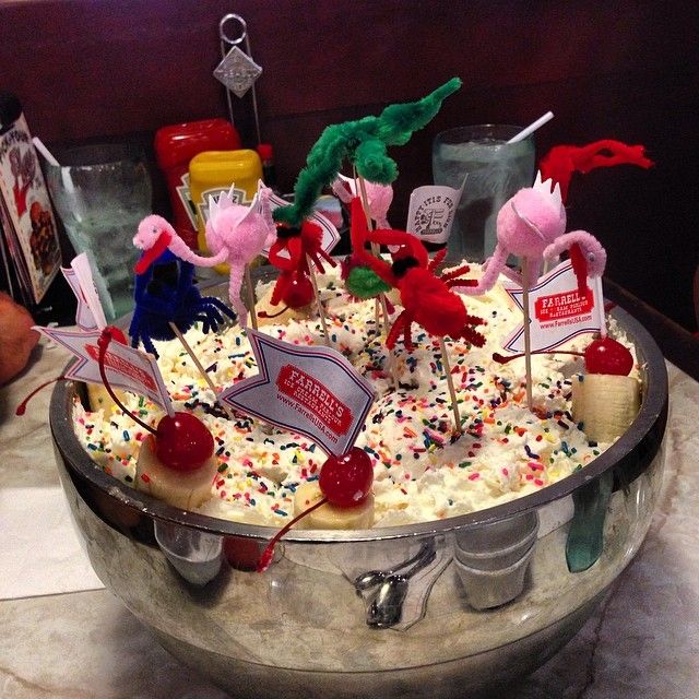 an ice cream sundae with sprinkles, cherries and dragon decorations