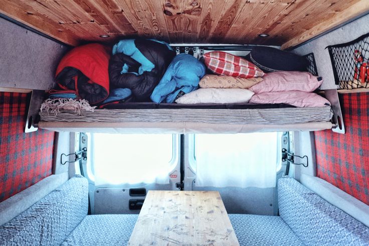 the inside of a camper with bunk beds and sleeping bags on it's side