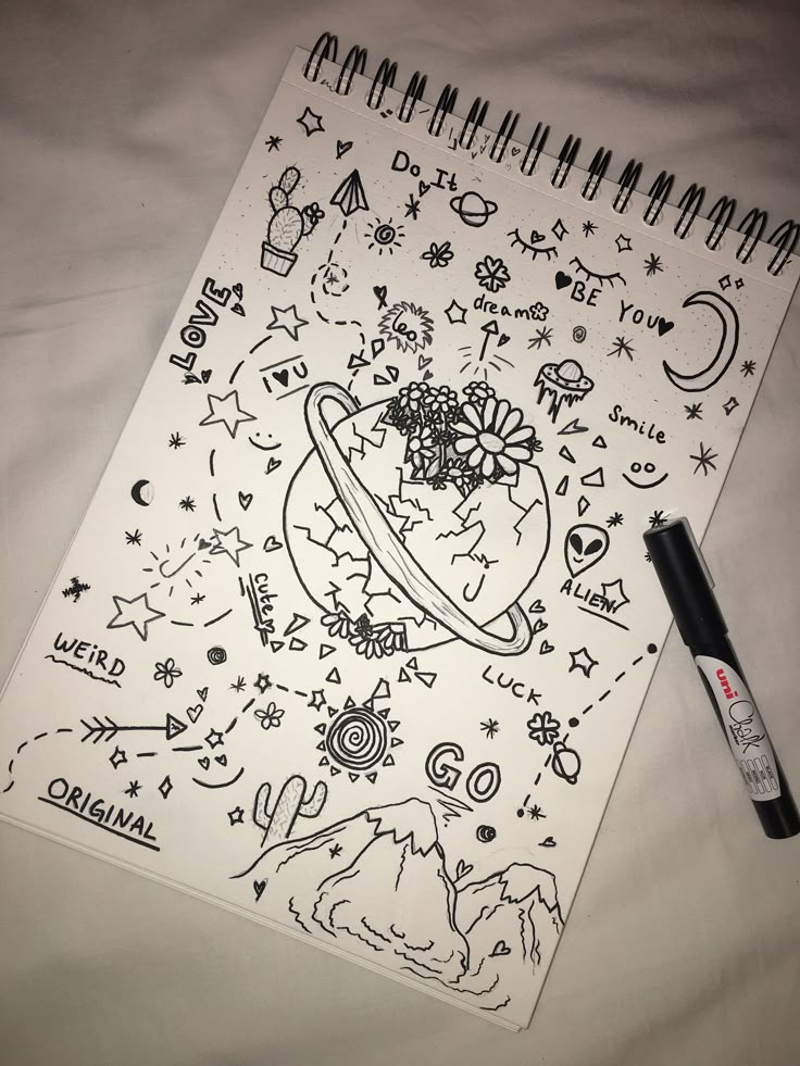 a notebook with drawings on it next to a marker