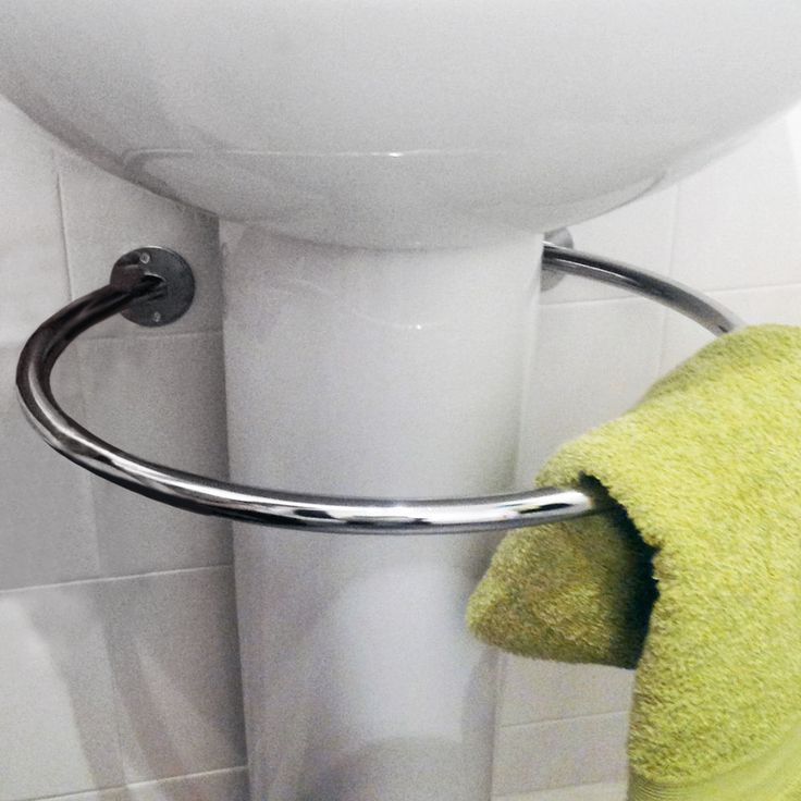 a green towel hanging on the side of a white toilet next to a metal holder