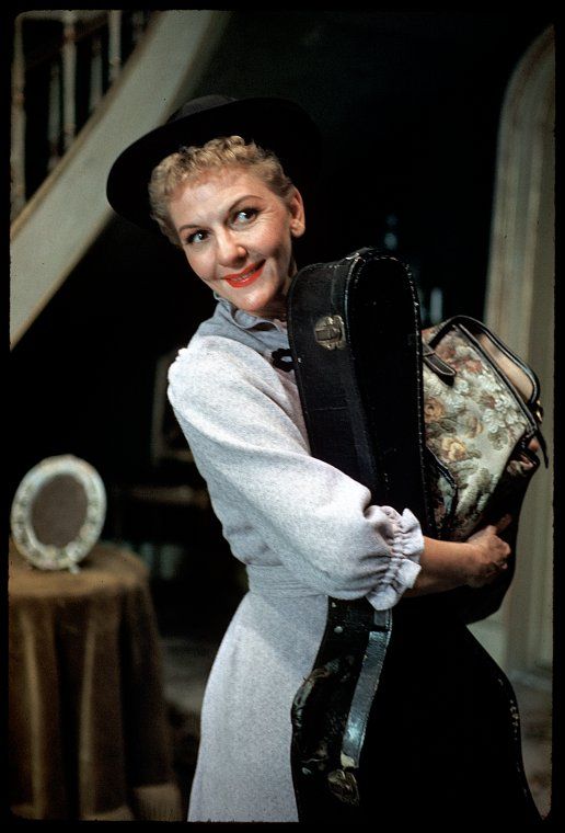 a woman in a white dress and black hat is holding a purse while posing for the camera