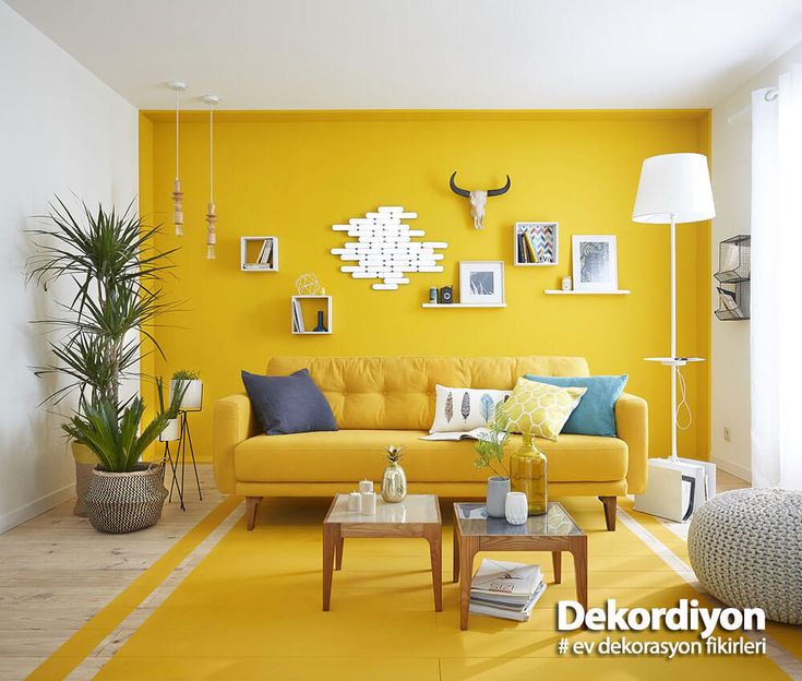 a living room with yellow furniture and pictures on the wall above it's coffee table