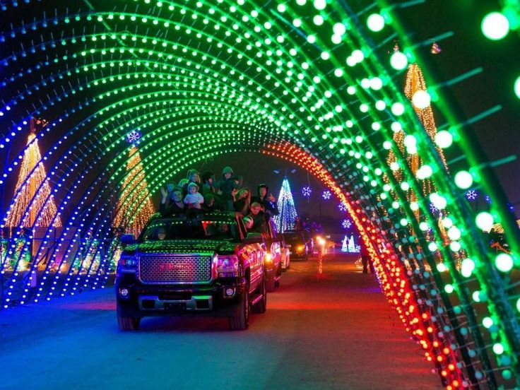 cars are driving down the road covered in christmas lights and decorated with green, red, and white lights