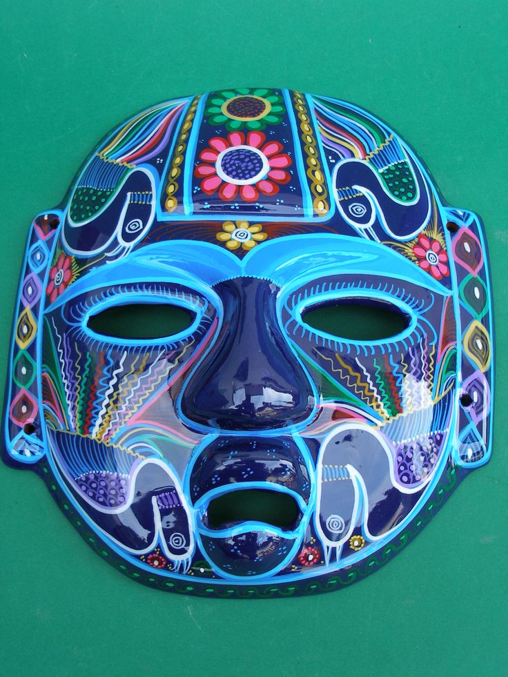 a blue mask with colorful designs on it sitting on a green surface, next to a tennis racket