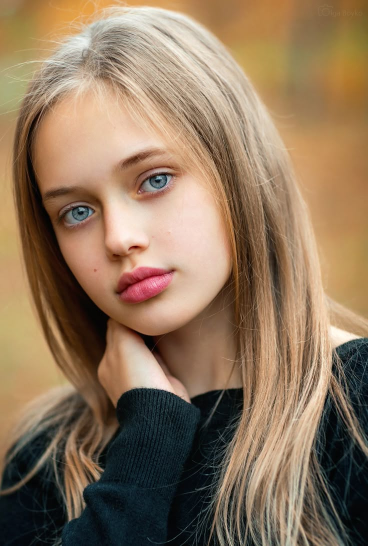 a woman with long blonde hair and blue eyes is posing for a photo in the fall