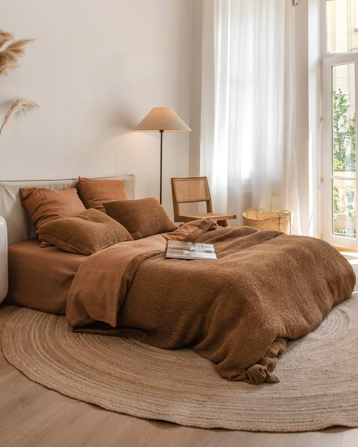 a bedroom with a bed, chair and lamp on the floor in front of a window