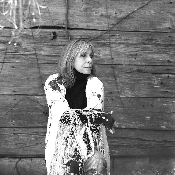 a woman standing in front of a wooden wall