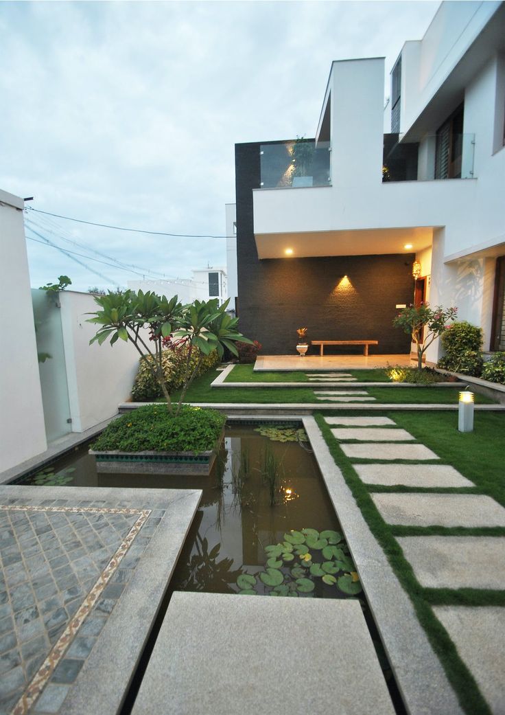 a house with a pond in the front yard and landscaping around it at night time