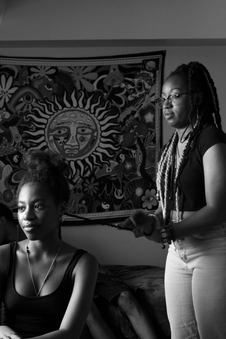 black and white photograph of three women in front of a wall hanging on the wall