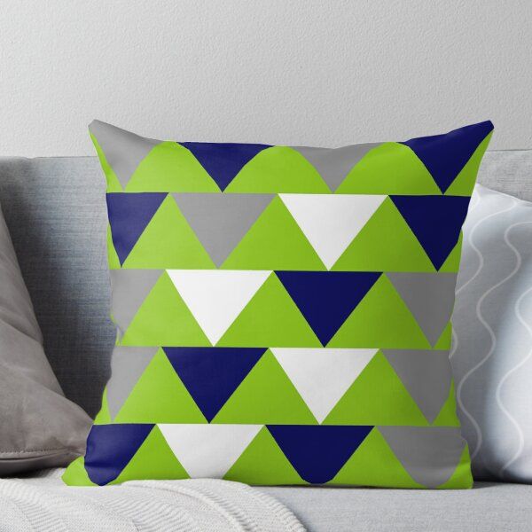 a green and blue throw pillow sitting on top of a couch