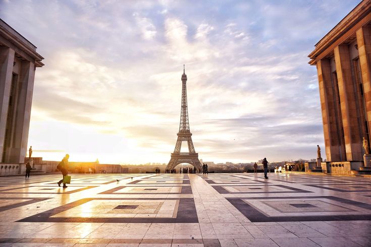 the eiffel tower in paris, france at sunset with people walking around it