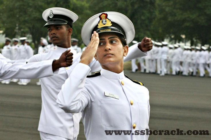 two navy officers saluting each other while others stand in the background with their hands together