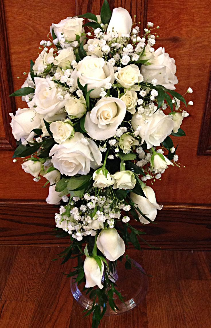 a vase filled with white flowers sitting on top of a wooden floor next to a door