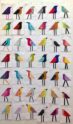 a quilt made with different colored birds on white paper and black thread, hanging from the wall