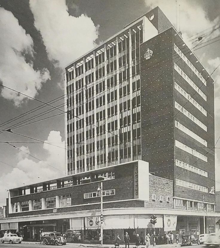 an old black and white photo of a large building on the corner of a street