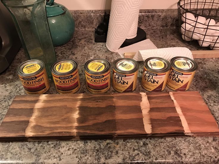 five jars of food sitting on top of a wooden cutting board next to a tea kettle