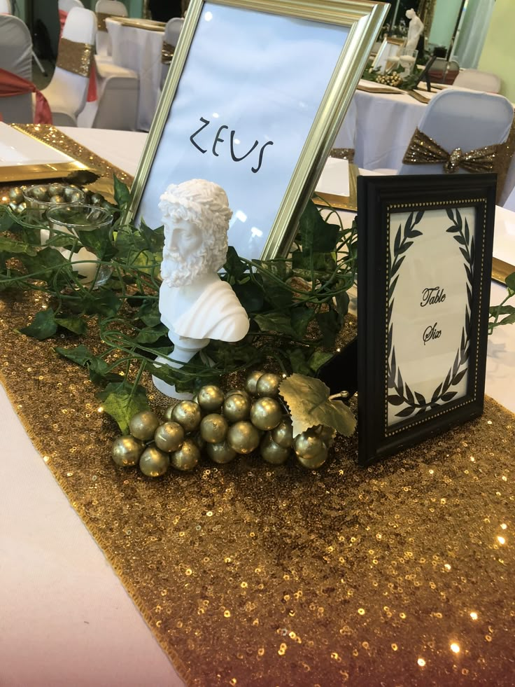 a table topped with a framed photo and gold ornaments next to a sign that says zesu