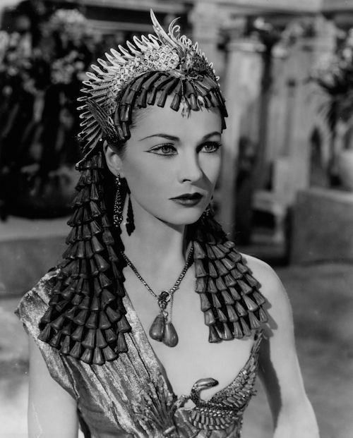 a woman wearing an elaborate headdress and large earrings is posing for the camera