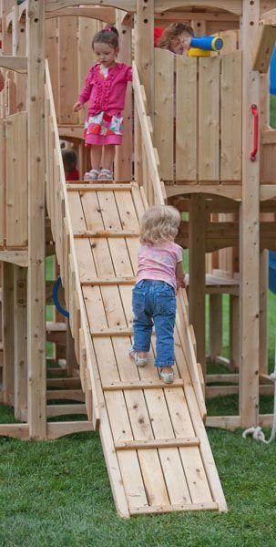 two children playing on a wooden play set