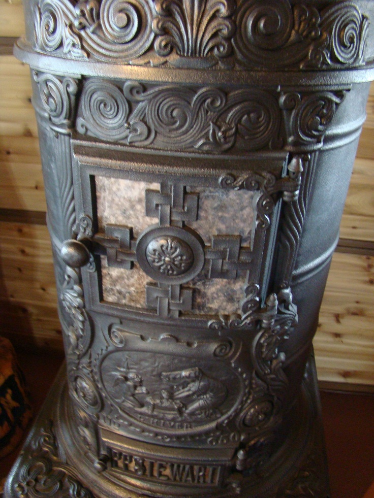 an old fashioned stove with ornate designs on it's front and back sides, sitting on a wooden table