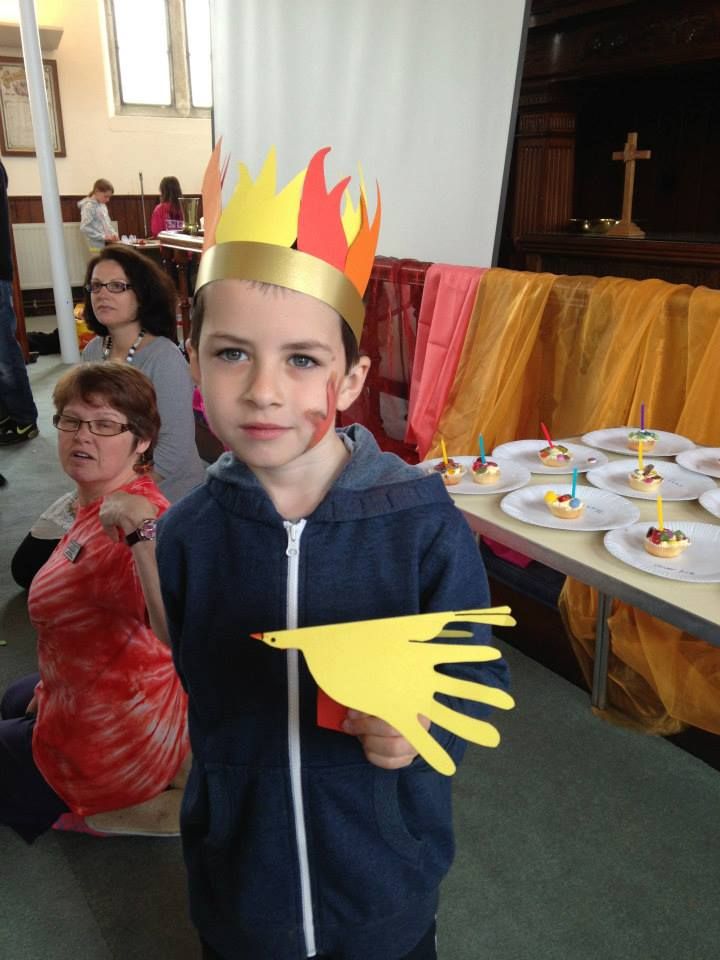 a young boy wearing a paper crown and holding up a piece of paper with flames on it