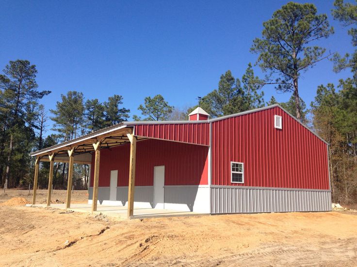 a large red barn sitting on top of a dirt field