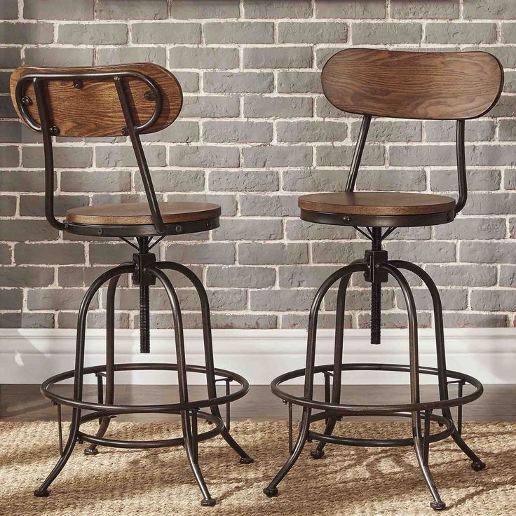 two wooden and metal barstools in front of a brick wall with a rug on the floor