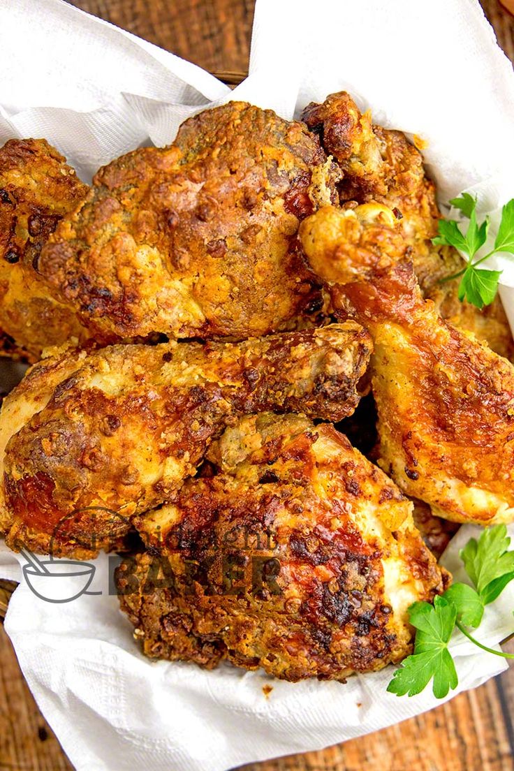 fried chicken wings with parsley in a basket on a wooden table, ready to be eaten