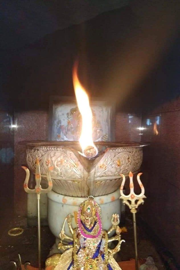 an idol sitting on top of a table next to a lit candle in the dark