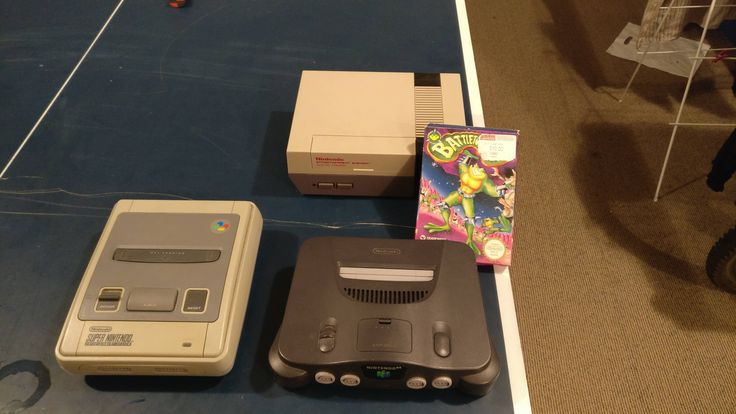 an old nintendo game console next to other electronic devices on a blue carpeted floor