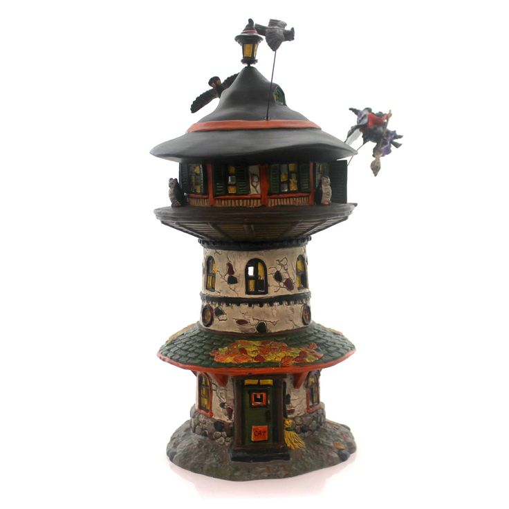 a small tower that is on top of a white surface and has two birds flying around it