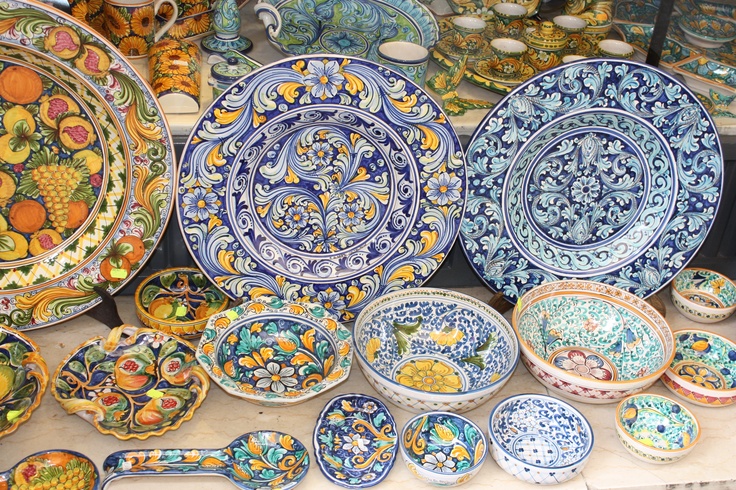 many plates and bowls are on display in a store window, some with designs painted on them