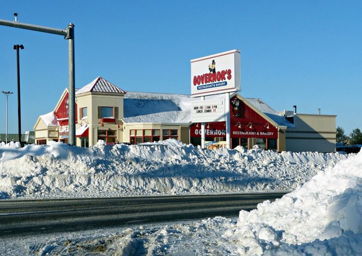 the snow is piled up on the side of the road in front of a building