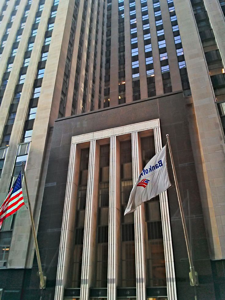 an american flag flies in front of the bank of america building, new york city