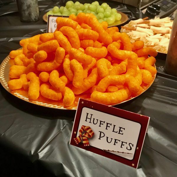 a platter filled with cheetos sitting on top of a table next to grapes