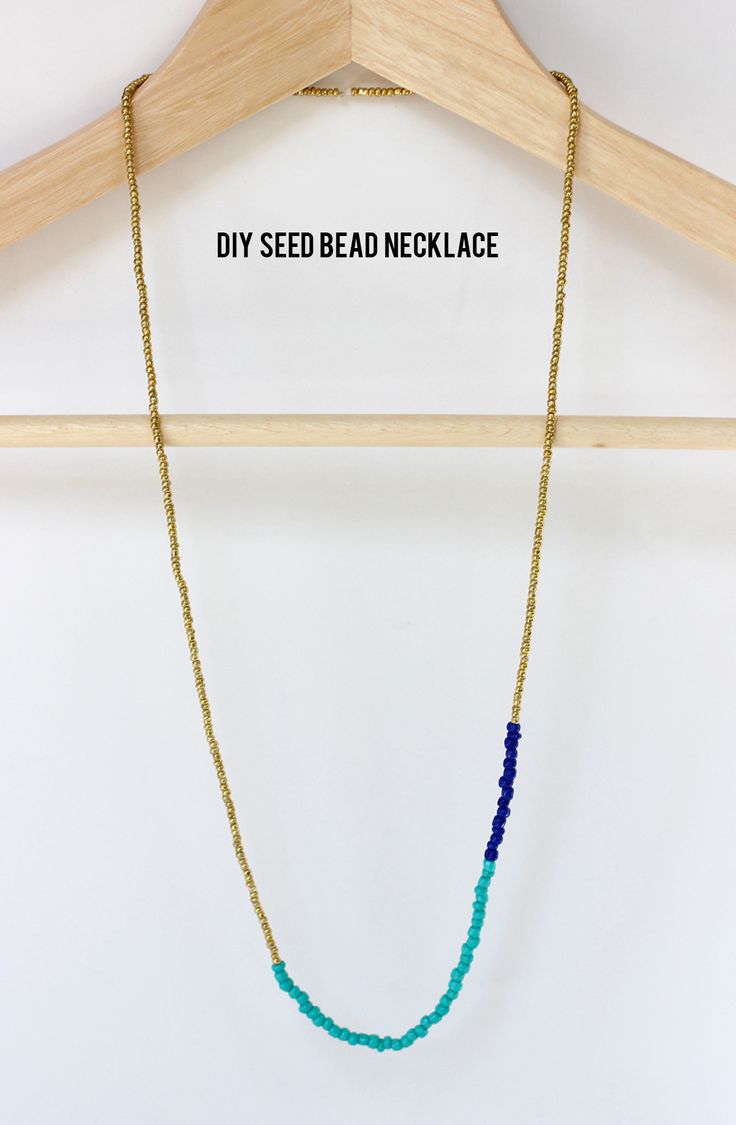 a necklace with beads hanging on a wooden hanger next to a sign that says diy seed necklace