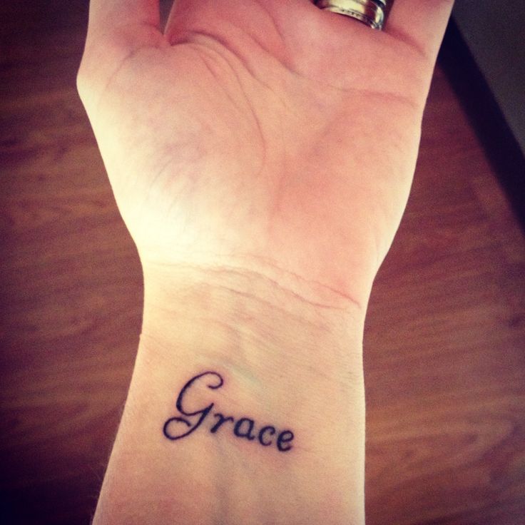 a small wrist tattoo with the word grace on it