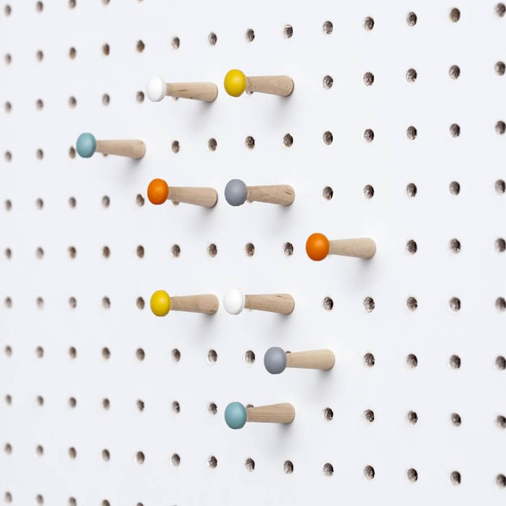 several wooden pegs are arranged on a white wall