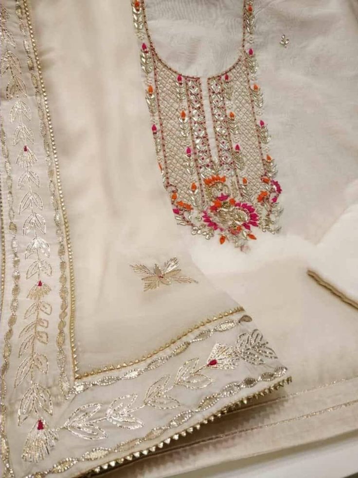 Item Overview ATHARVA Hand Embroidery Salwar Kameez/Beige Chanderi Silk/Gota Patti Chiffon Chinon Dupatta/Custom Stitch Unstitch/Churridar/Anarkali Dno. CH1752 Fabric: * Shirt - Chanderi Silk- Hand Embroidered Neck 2.5 Mts - Beautiful Hand Embroidery * Dupatta: Chiffon Chinnon Dupatta- All over Exclusive Gota Patti Embroidery - 2.5 Mts- Latkans Tassels * Bottom Santoon Silk 2.5 Mts. Excusive Hand Embroidered Party Wear Punjabi Suit. Customization: * Fabrics Customization: Designs Can be made in Beige Gota Work Anarkali Set For Wedding, Beige Anarkali Set With Gota Work For Wedding, Unstitched Off White Kurta With Mirror Work, Off White Chanderi Traditional Wear With Gota Work, Off White Traditional Wear With Gota Work For Eid, Off White Chanderi Sets With Mirror Work, Semi-stitched Cream Sharara For Transitional Season, Designer Cream Churidar With Gota Work, Festive Off White Salwar Kameez With Gota Work