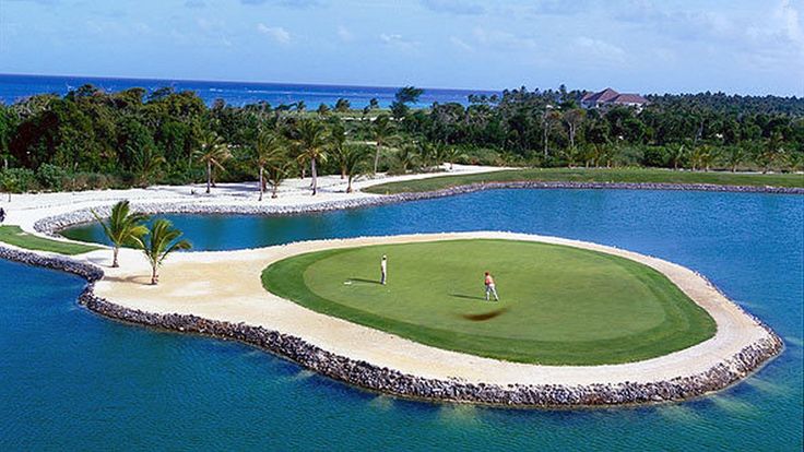 an aerial view of a golf course in the middle of some water and palm trees